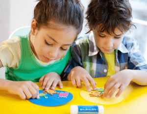 A boy and a girl are sitting at a table making crafts.