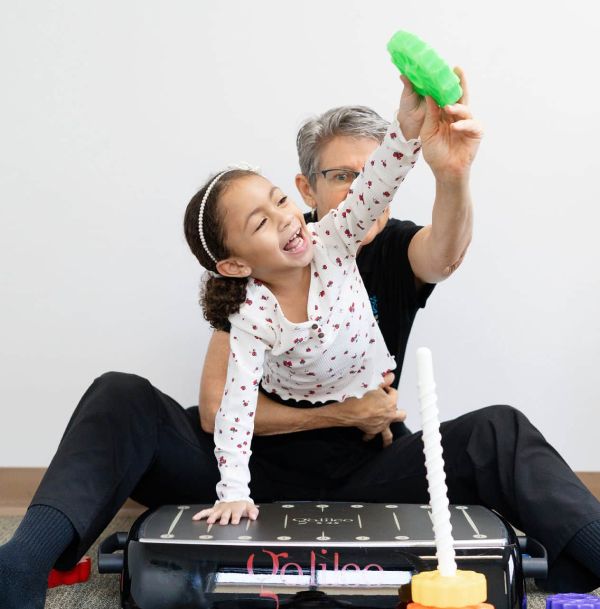 A little girl is sitting on a man 's lap holding a green object