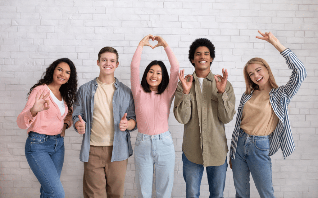 A group of young people are making a heart shape with their hands.