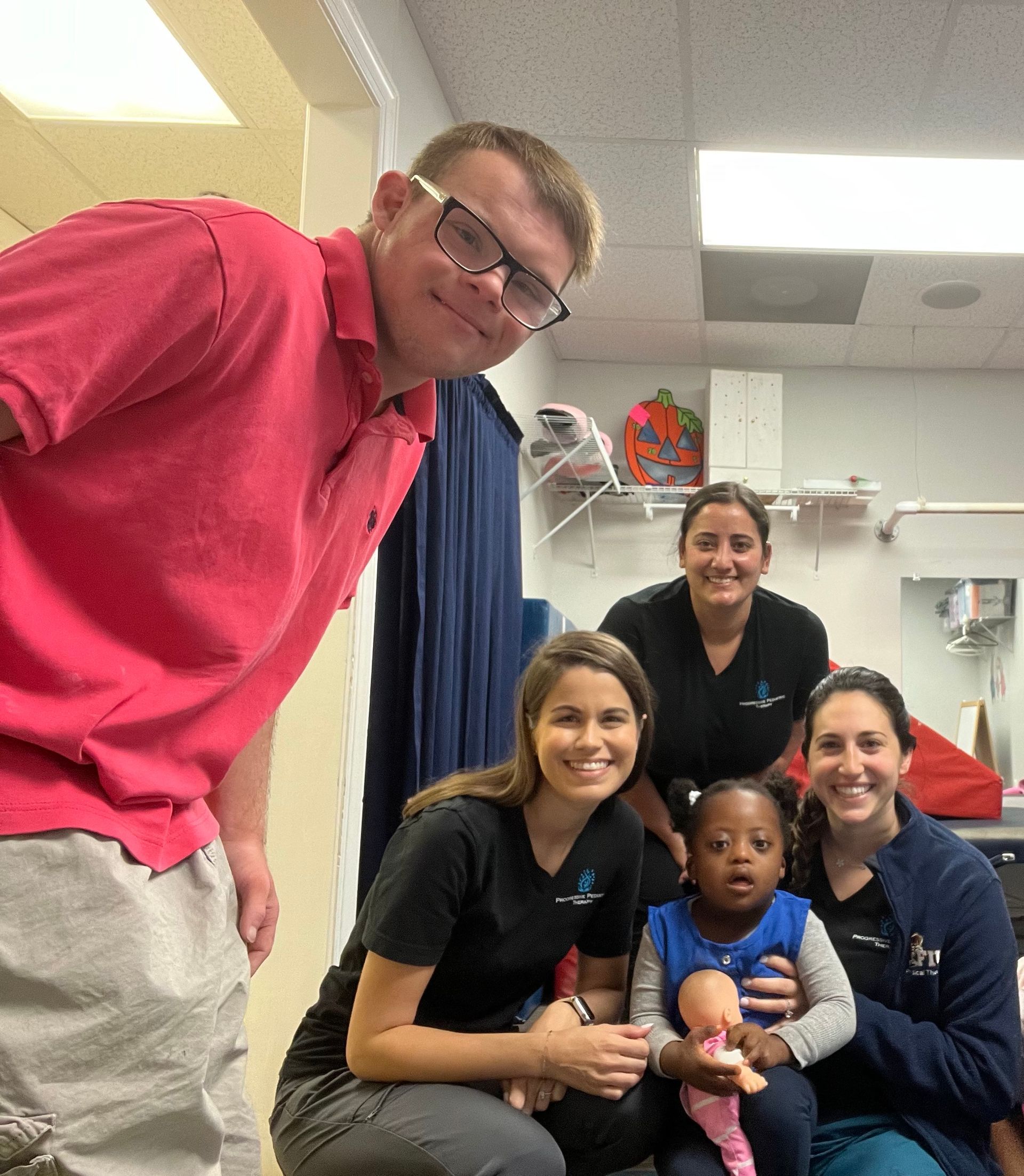 A group of people posing for a picture including a man in a pink shirt