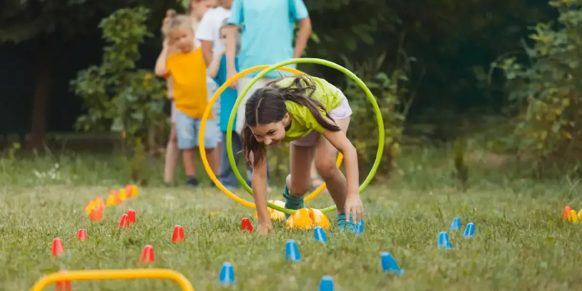 A girl is playing with a hula hoop in the grass.