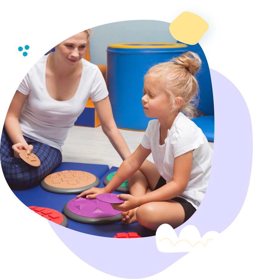 A woman and a little girl are sitting on the floor playing with toys.