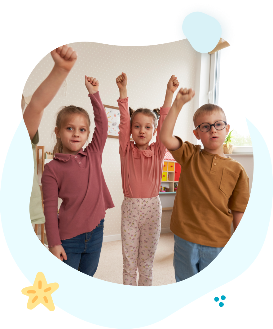 A group of children are standing next to each other with their hands in the air.