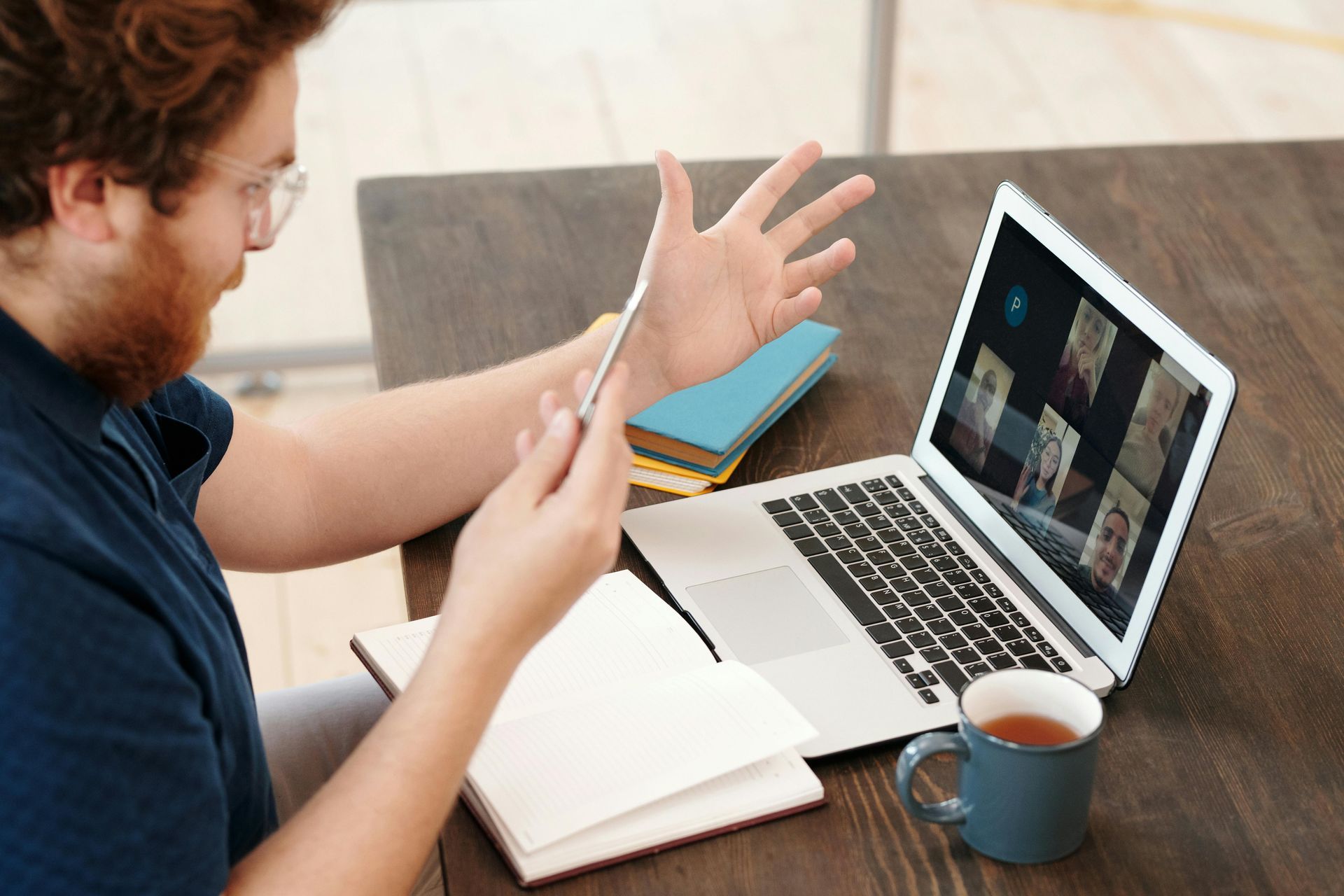 A man is sitting at a table using a laptop and a tablet.