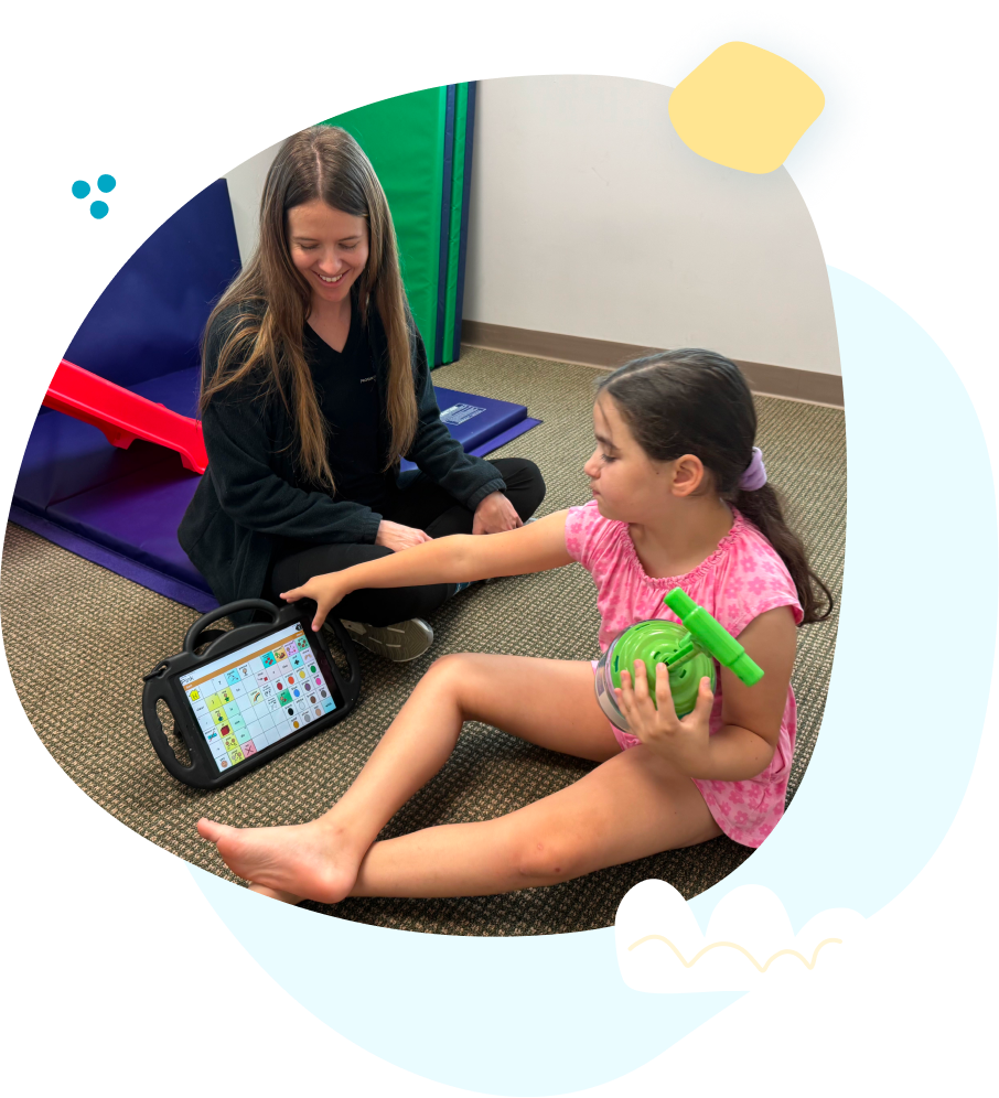 A girl is sitting on the floor holding a green ball and a tablet.