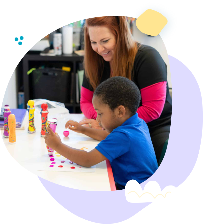 A woman is helping a young boy with a craft.
