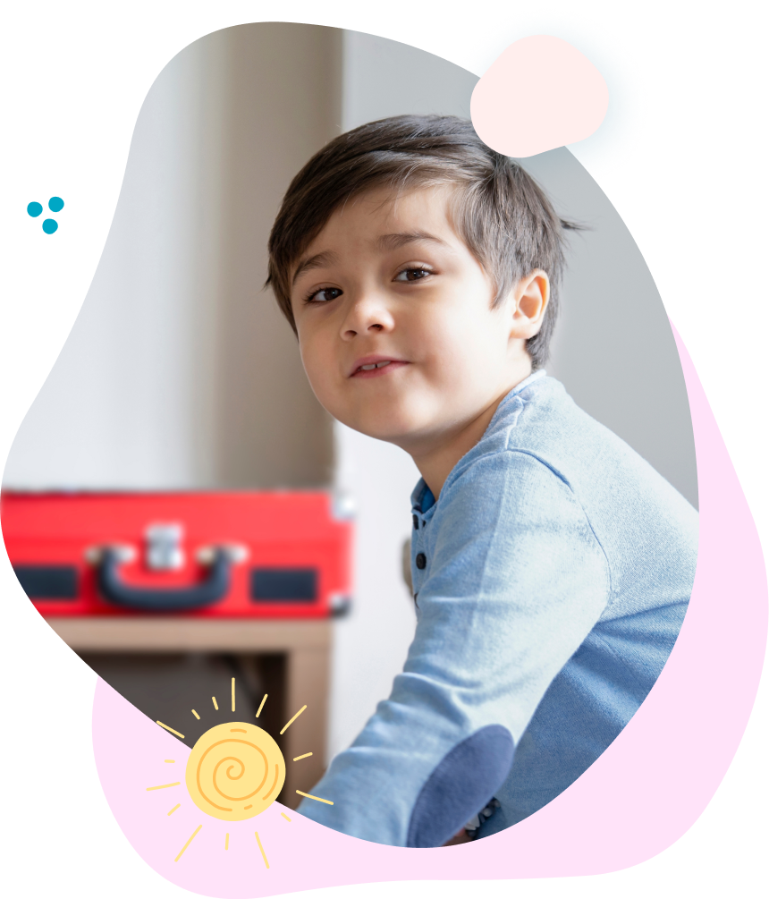 A young boy is sitting in front of a red suitcase.
