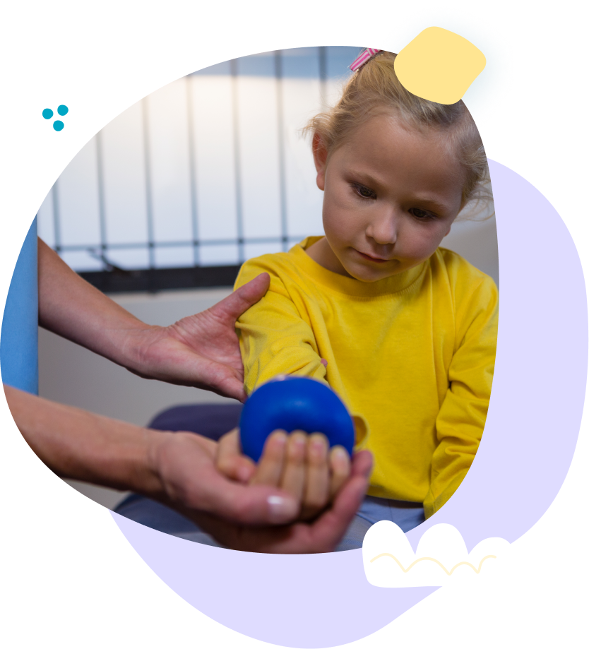 A little girl is holding a blue ball in her hands.