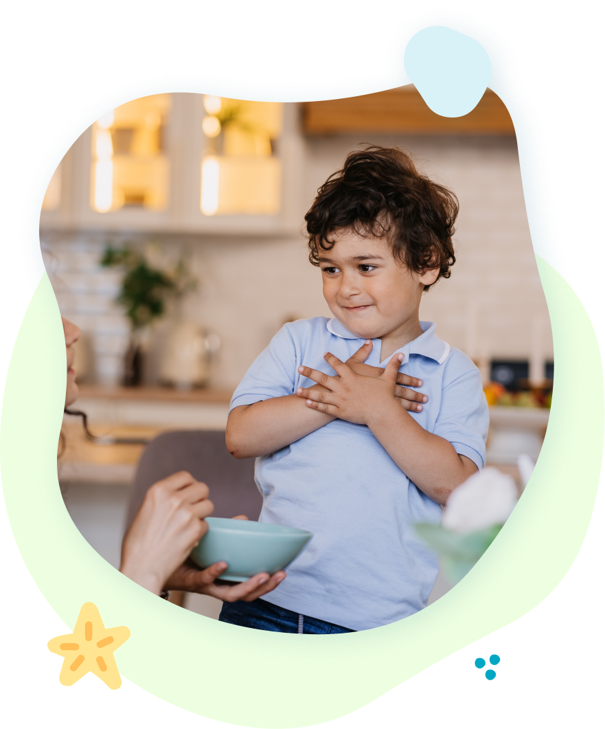 A little boy is standing in front of a bowl of food.
