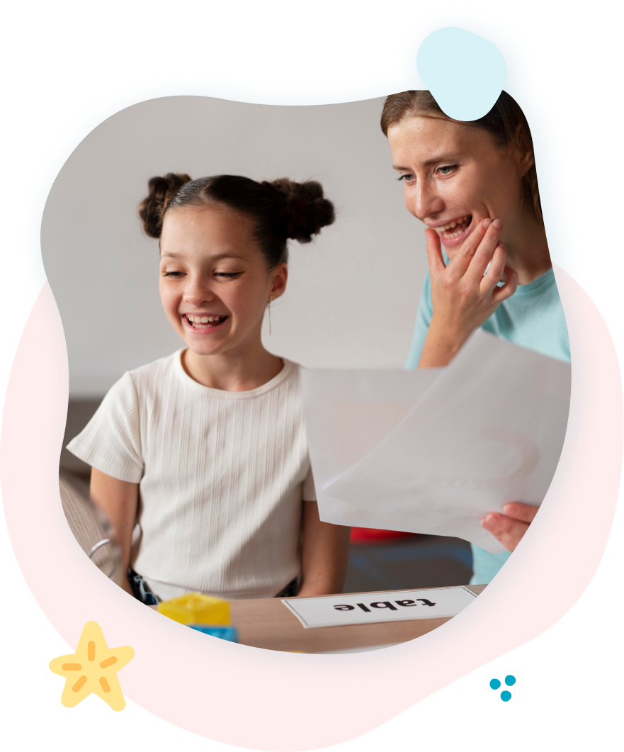 A woman and a little girl are sitting at a table looking at a piece of paper.