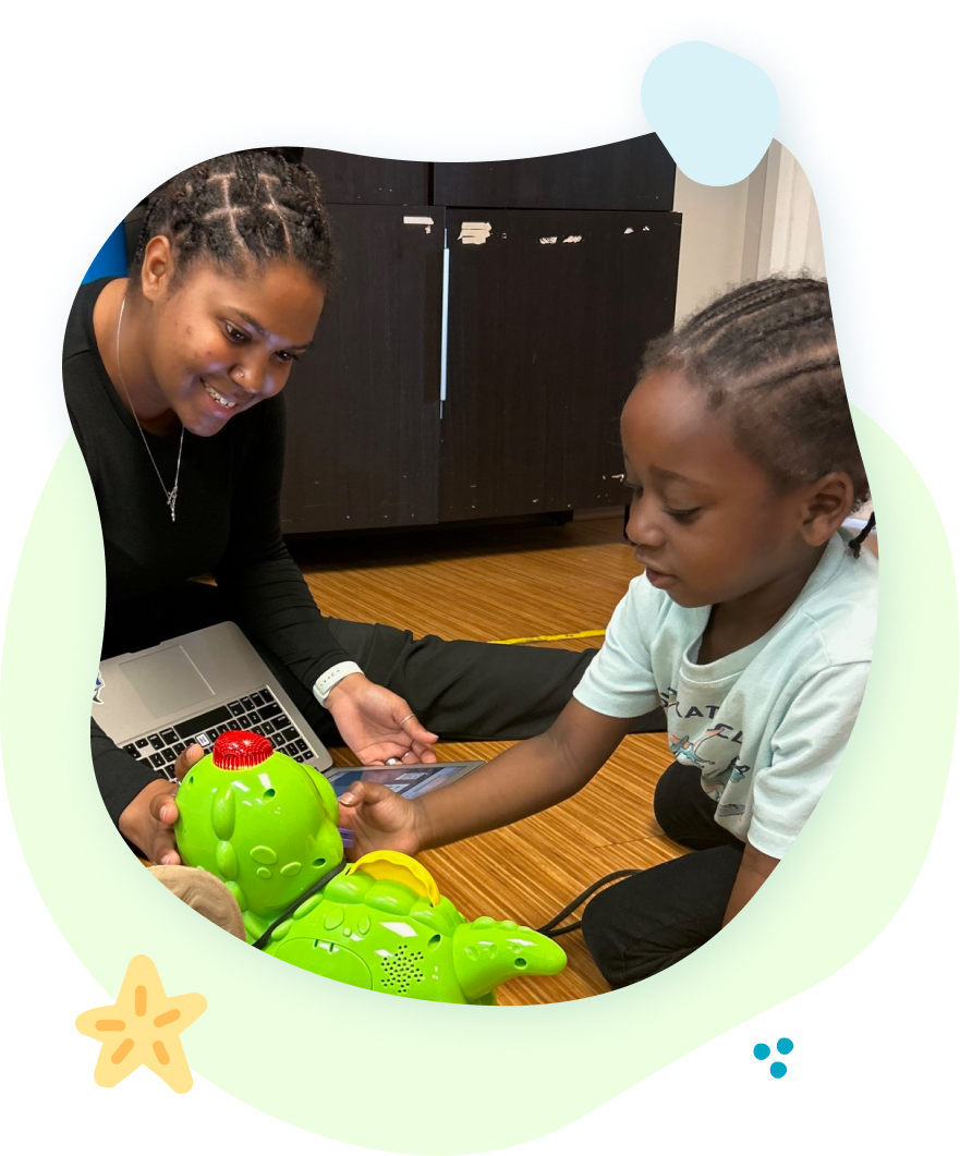 A woman and child are playing with a toy frog on the floor.