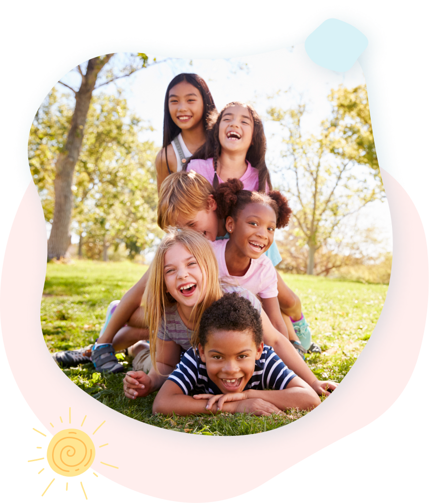 A group of children are laying on top of each other in the grass.