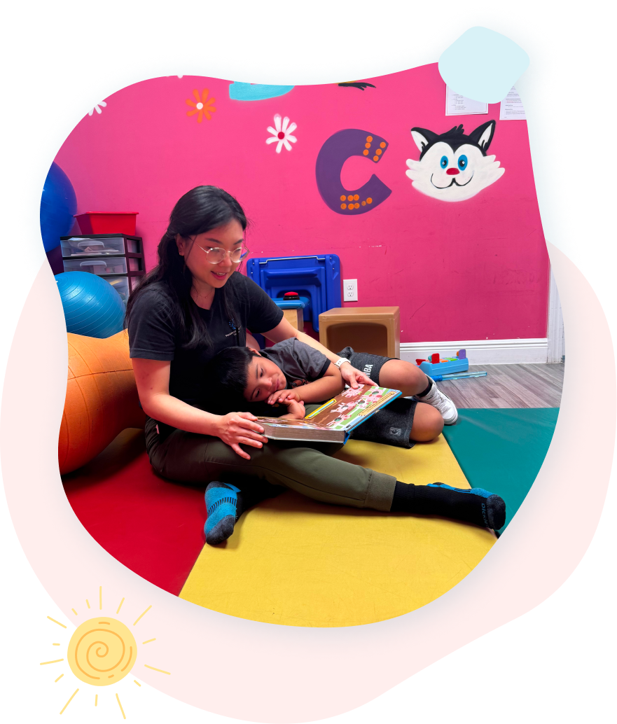 A woman sits on the floor reading a book to a child