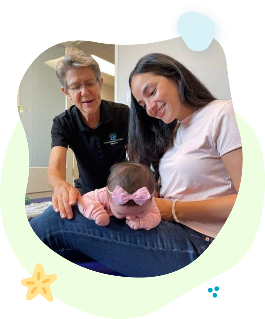 A woman is holding a baby while another woman looks on.
