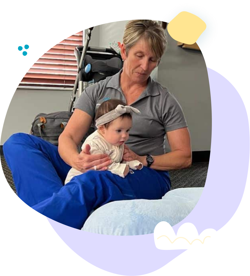 A woman is sitting on the floor holding a baby.