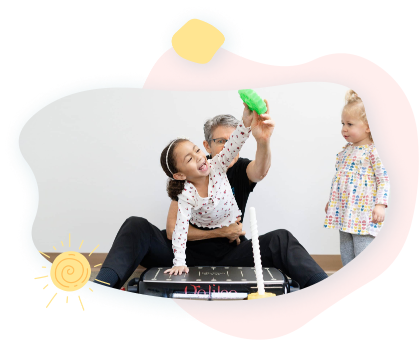 A man and two little girls are playing with a green toy.