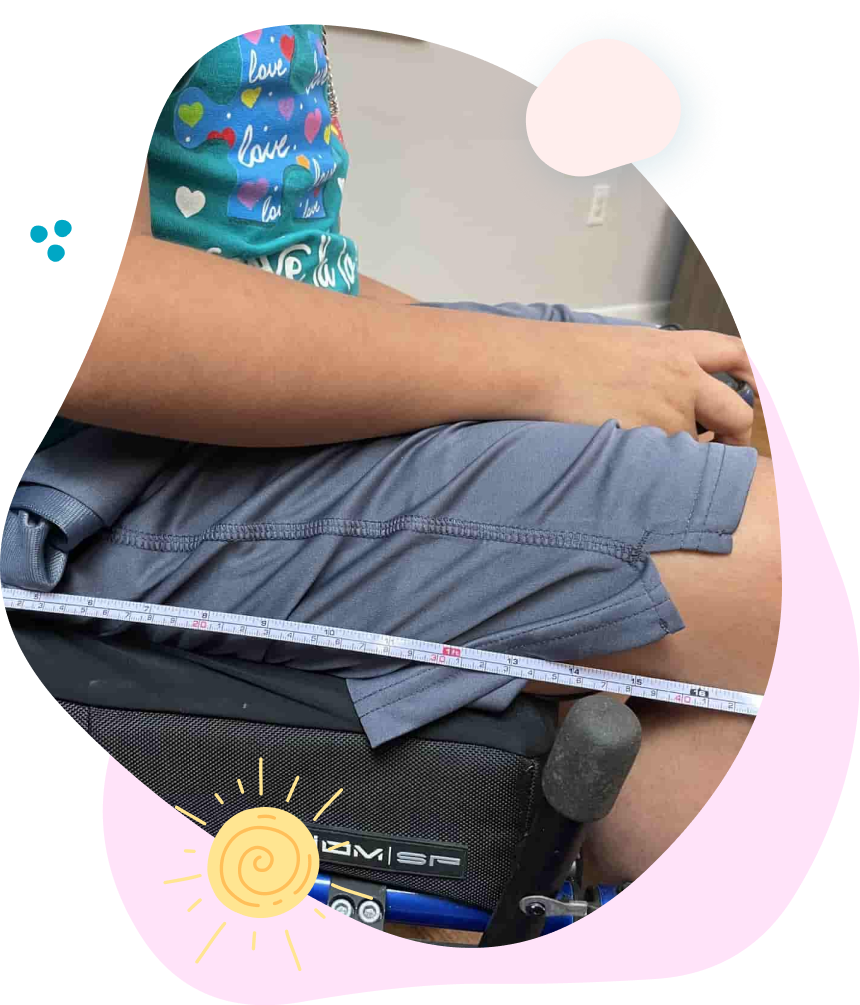 A person in a wheelchair is measuring their thigh with a tape measure.