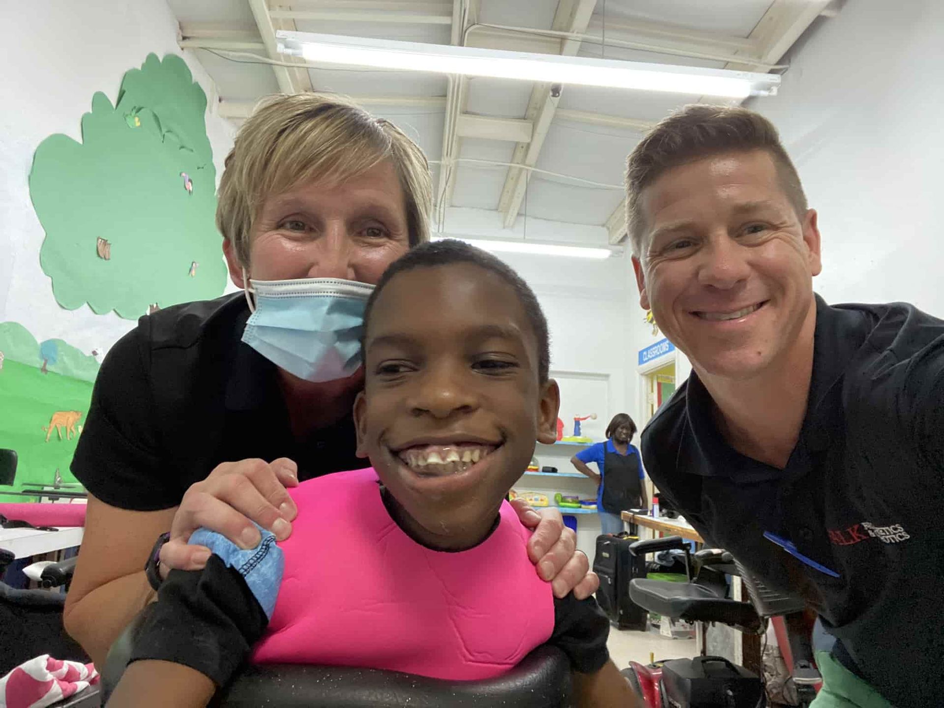 A man and a woman are posing for a picture with a boy in a wheelchair.