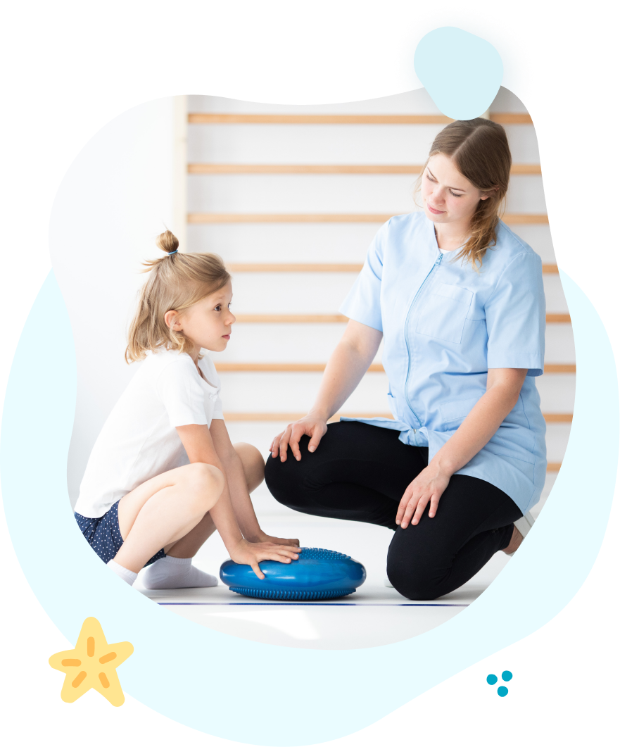 A woman is kneeling down next to a little girl playing with a blue pillow.