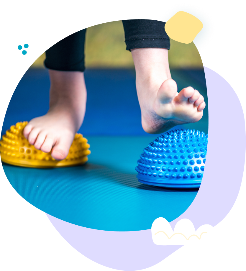 A child 's feet are standing on a blue and yellow balance ball.