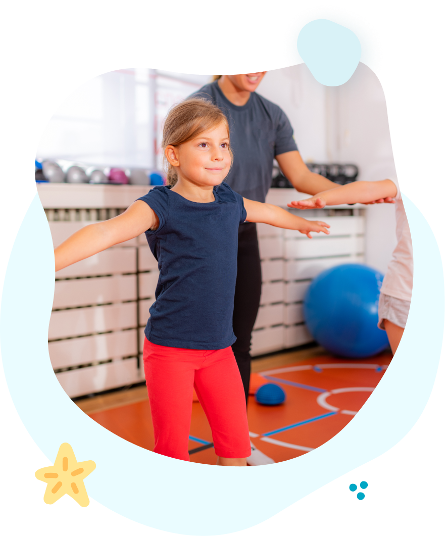A little girl is standing in a gym with her arms outstretched.