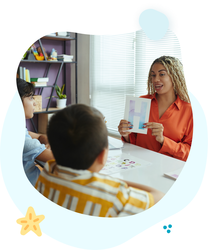 A woman is sitting at a table teaching a group of children.