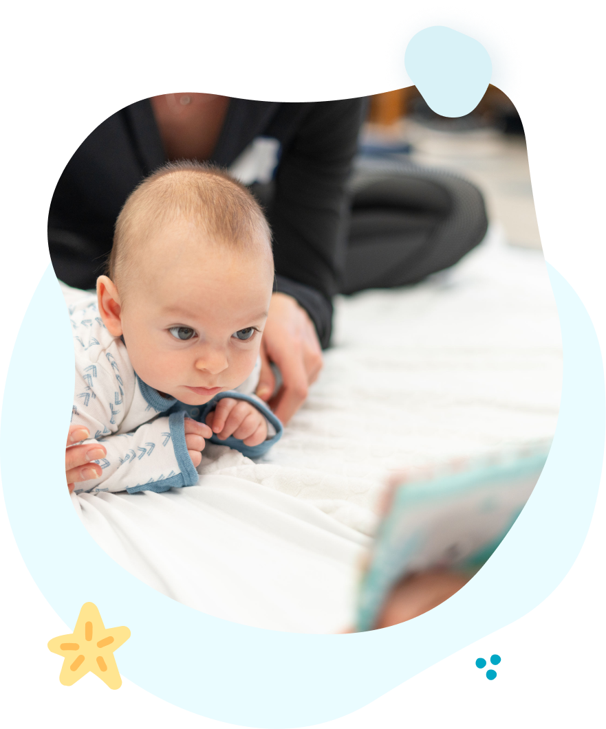 A baby is laying on a bed looking at a book.