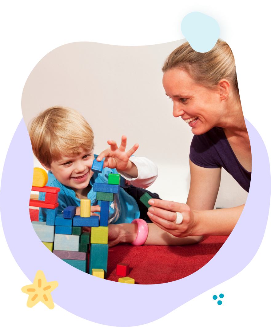 A woman is playing with a child who is playing with blocks.