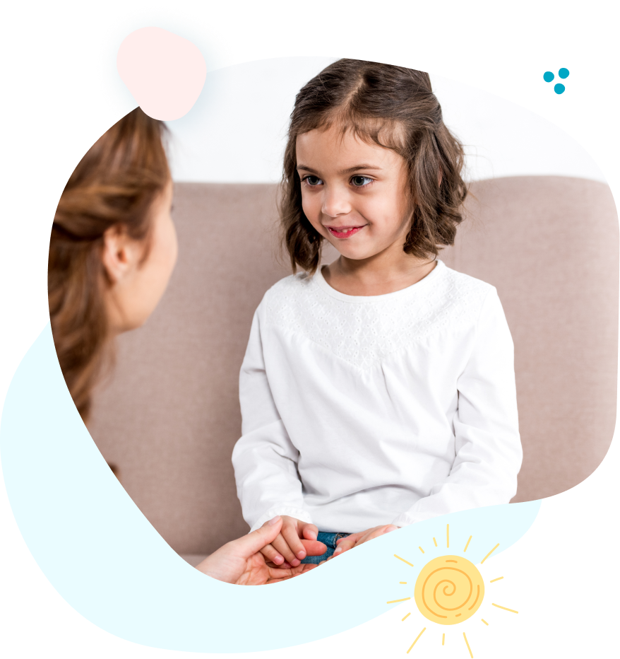 A little girl is sitting on a couch holding a woman 's hand.