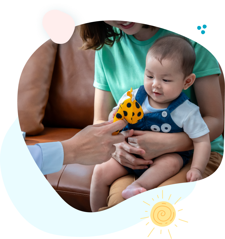 A baby is sitting on a couch being held by a woman.