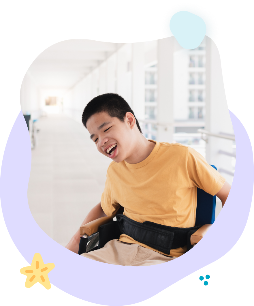 A young boy is sitting in a wheelchair and smiling.