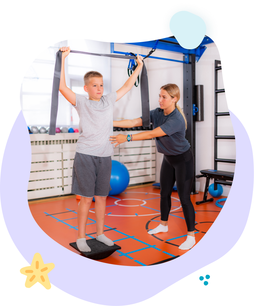 A woman is helping a young boy do exercises in a gym.