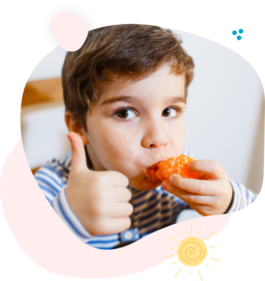 Young child eating orange slice, giving a thumbs up.