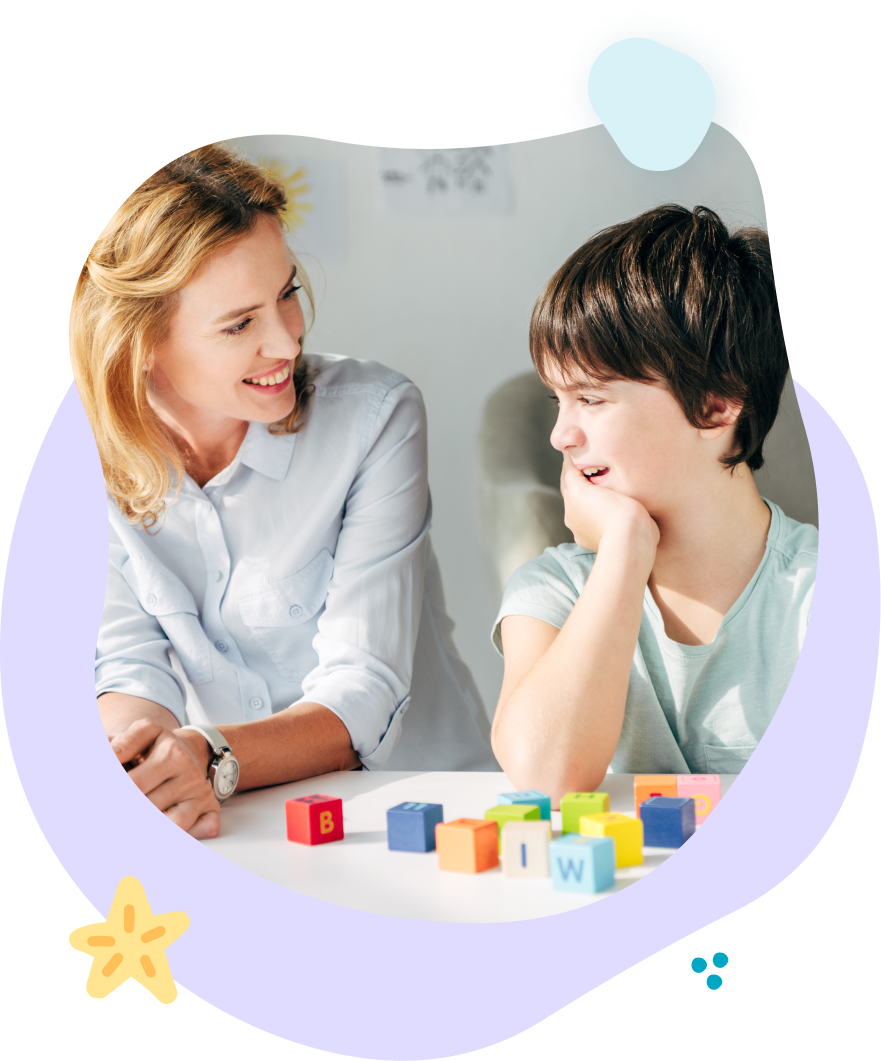 A woman and a boy are sitting at a table with blocks.