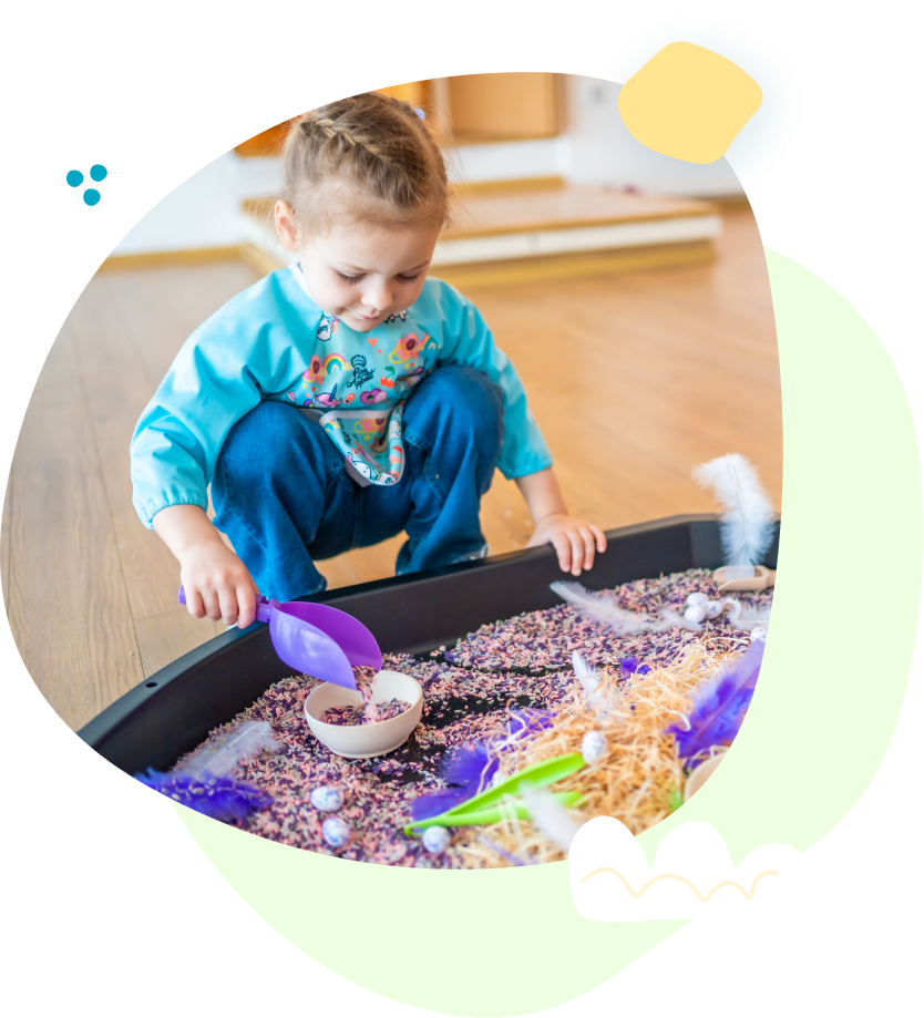 A little girl is playing in a sensory bin.