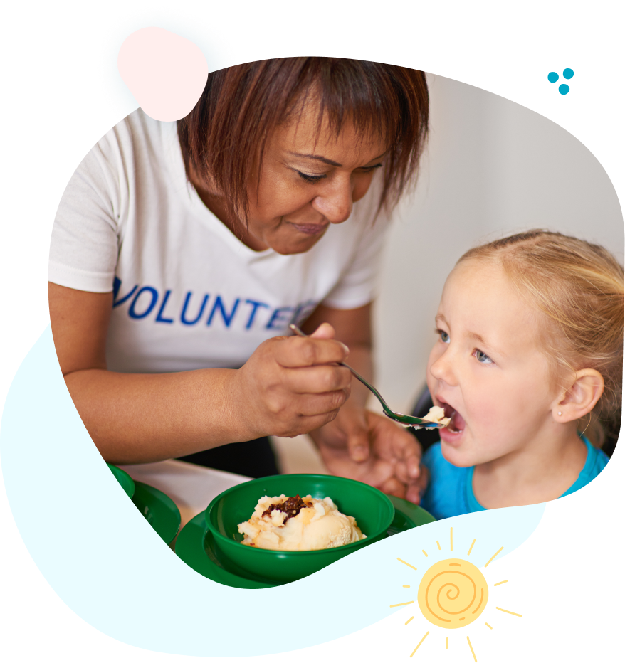 A woman is feeding a little girl with a spoon.