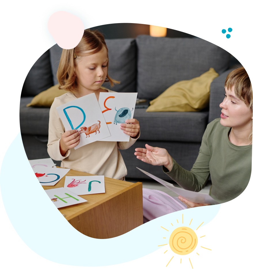 A woman is teaching a little girl how to read the alphabet.