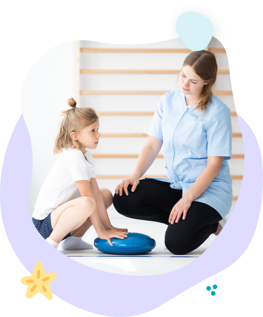 A woman is kneeling down next to a little girl playing with a blue pillow.