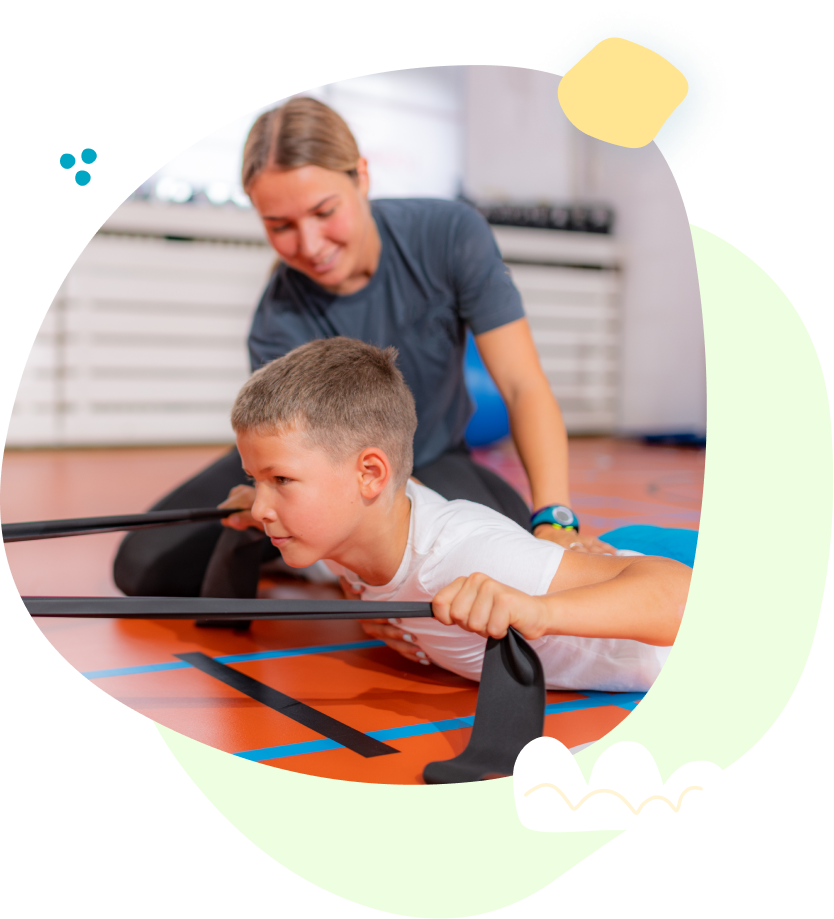 A woman is helping a young boy do exercises on the floor.