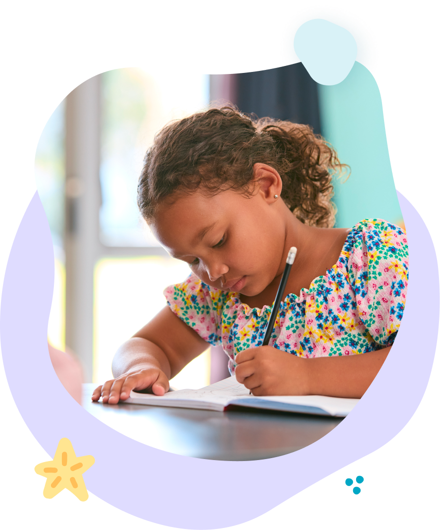 A little girl is sitting at a table writing in a notebook.