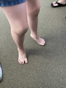 A woman 's bare feet are standing on a carpet.