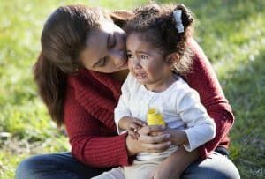 A woman is holding a crying baby in her arms.