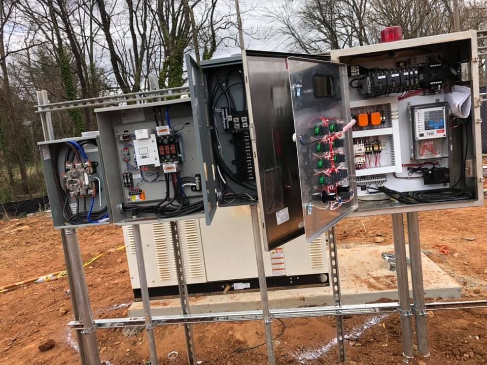 A bunch of electrical boxes are sitting on top of each other in a field.