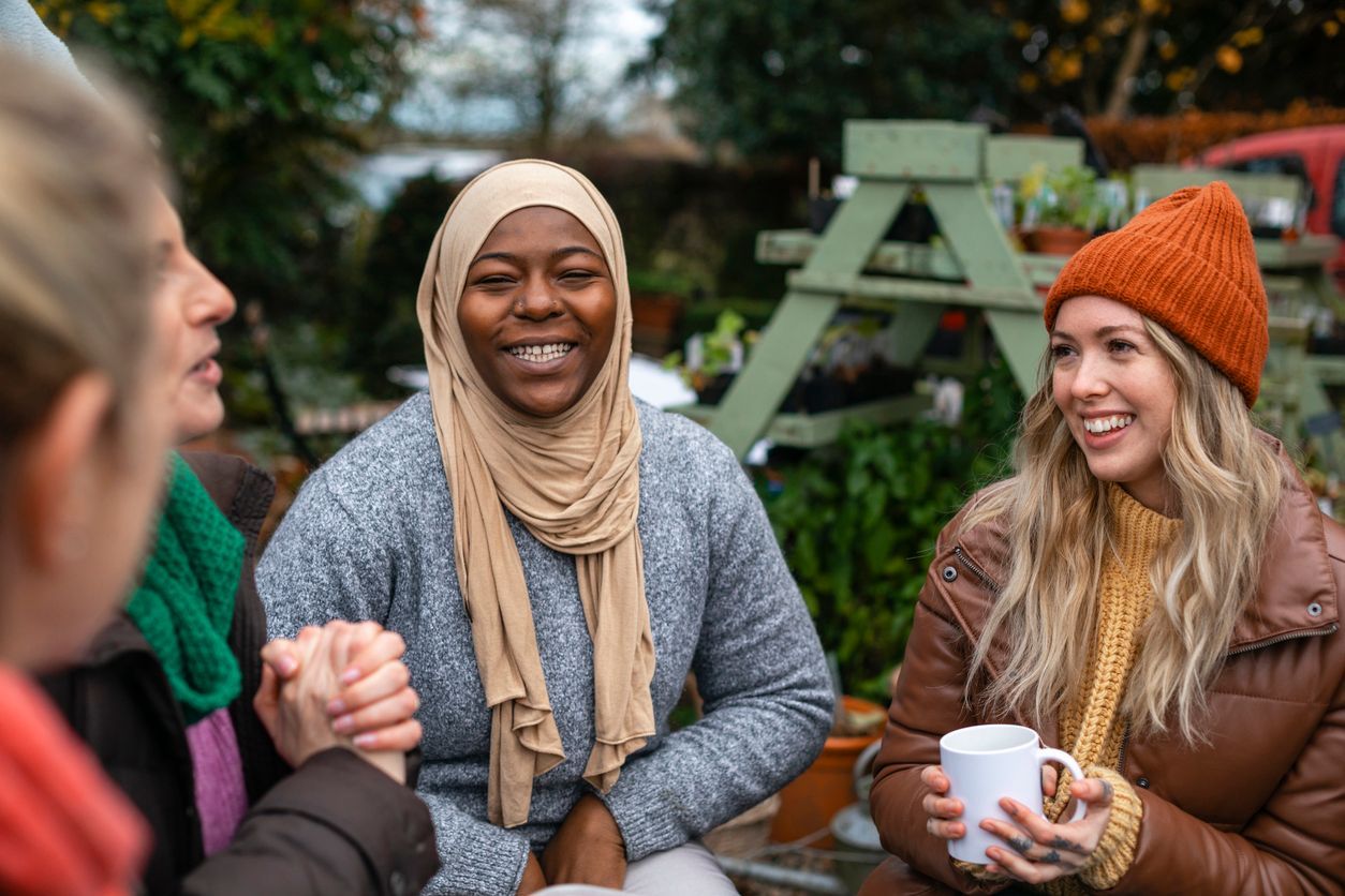 A group of women are sitting around a table holding hands.