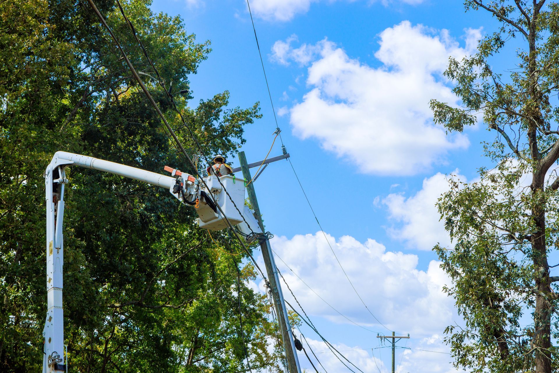 A man in a bucket is working on a power line.