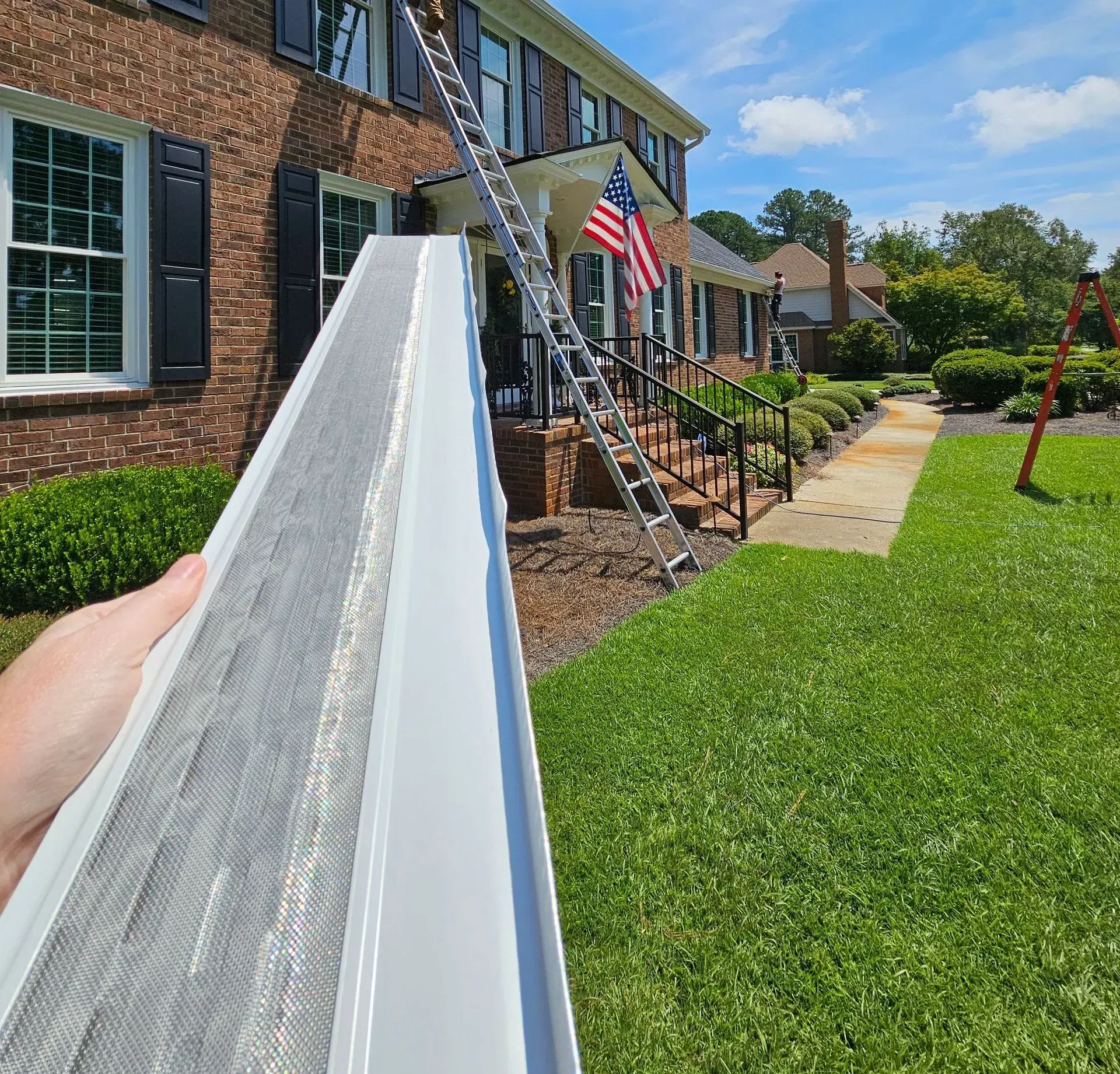 A person is holding a gutter cleaner in front of a house.