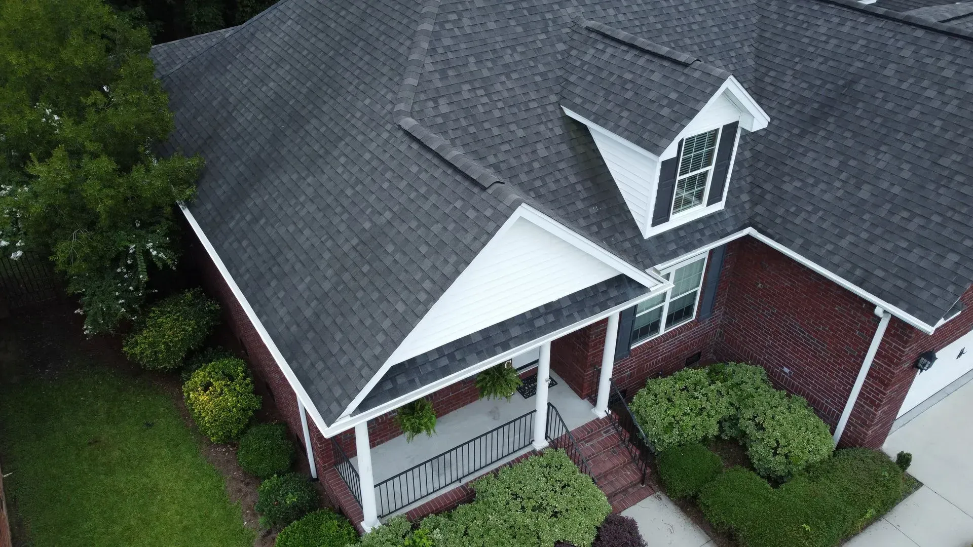 An aerial view of a brick house with a black roof.