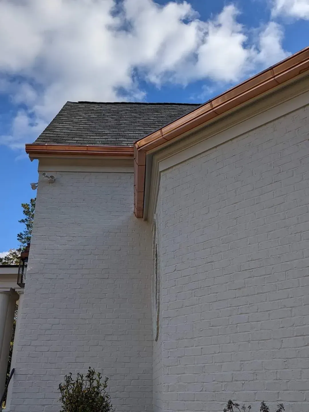 A white brick building with a copper gutter on the side