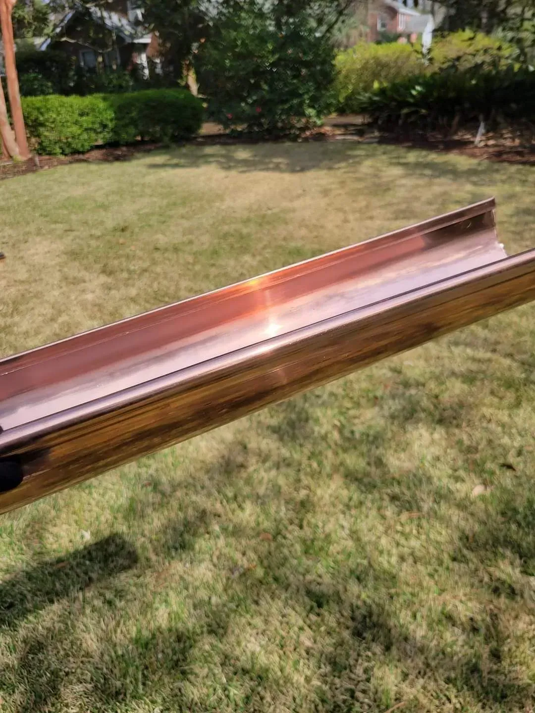 A copper gutter is sitting on top of a lush green field.