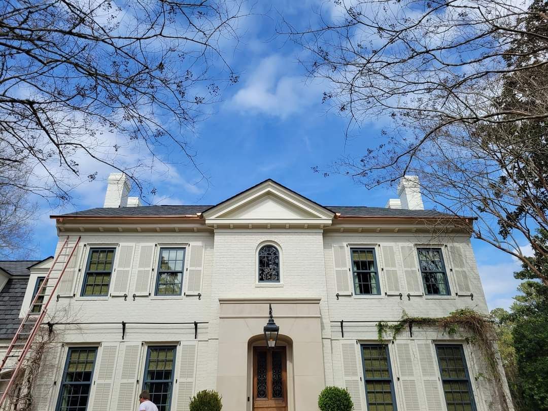 A man is standing in front of a large white house.